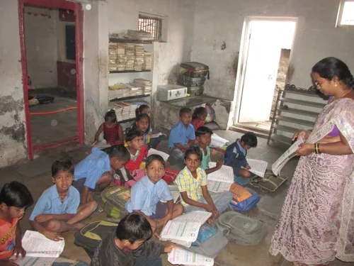 Ms Kamble teaching a group of children seated together in the classroom